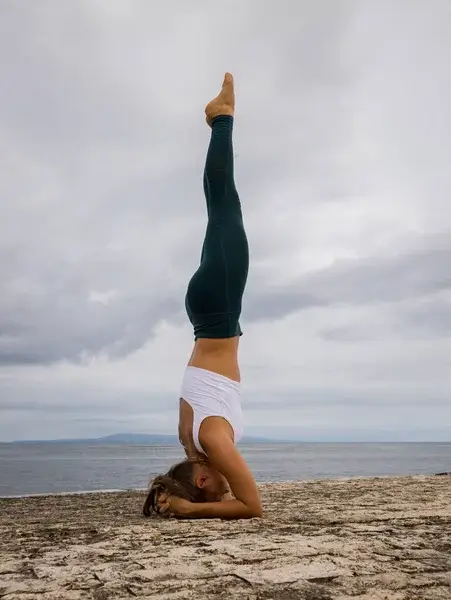 woman practicing handstand on the beach